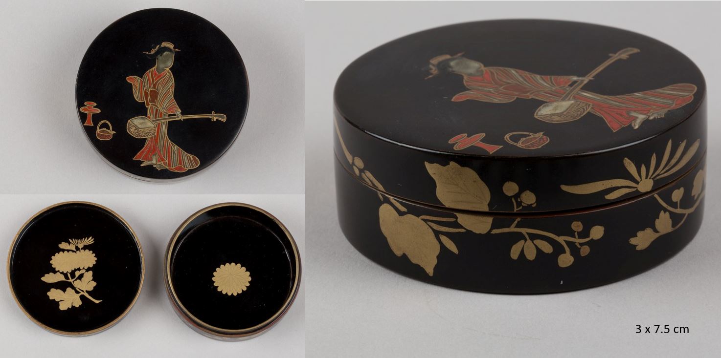 Cylindrical etui with lid, decorated with gold, silver, and red togidashi on a black ground. Outside decoration on the lid depicting a woman playing shamisen and inside a chrysanthemum. The sides with leaves and floral design.